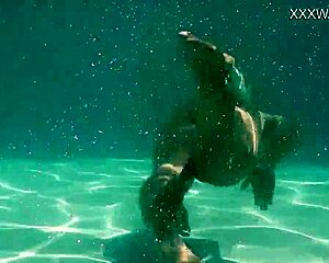 Small statured brunette swims in the pool and pleases herself