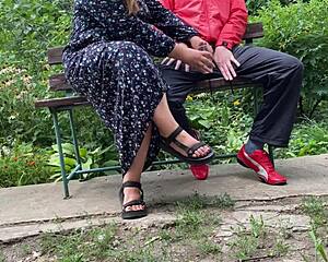 Woman pleasures man into glass in park on bench
