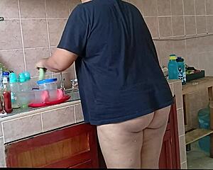 Chubby stepmom washes dishes and cleans kitchen